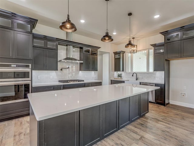 5812 Cimarron Mnr, Guthrie, OK 73044 - kitchen featuring tasteful backsplash, light wood-type flooring, light countertops, wall chimney exhaust hood, and recessed lighting