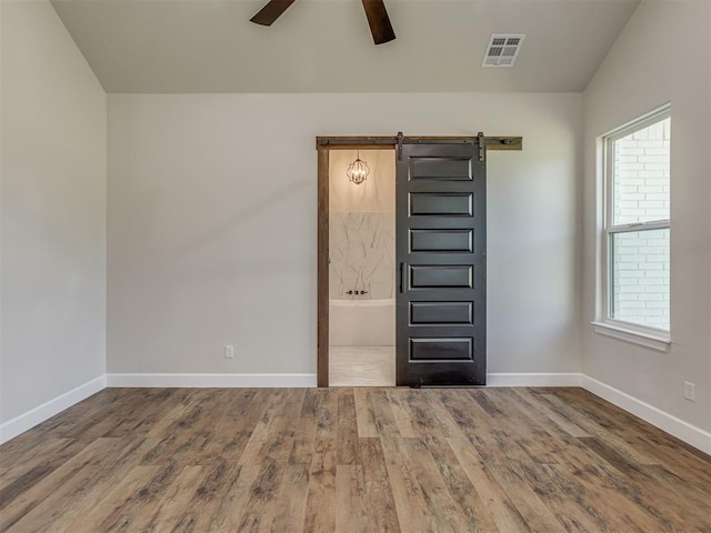 5812 Cimarron Mnr, Guthrie, OK 73044 - unfurnished room featuring ceiling fan, a barn door, wood finished floors, and plenty of natural light