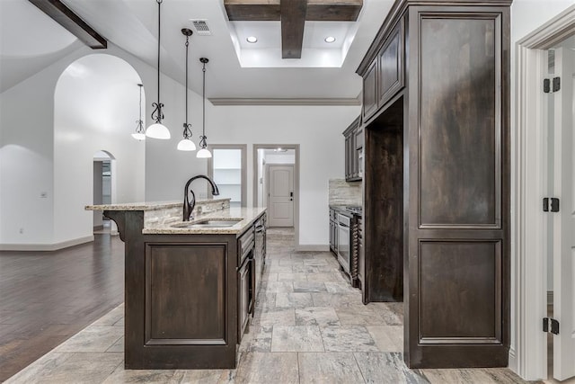 328 SW 175th Ter, Oklahoma City, OK 73170 - kitchen featuring a sink, arched walkways, dark brown cabinetry, baseboards, and beamed ceiling