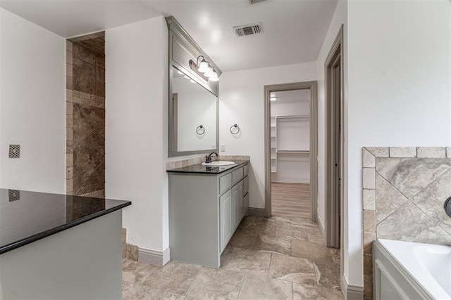 328 SW 175th Ter, Oklahoma City, OK 73170 - bathroom with vanity, a garden tub, baseboards, and a walk in closet
