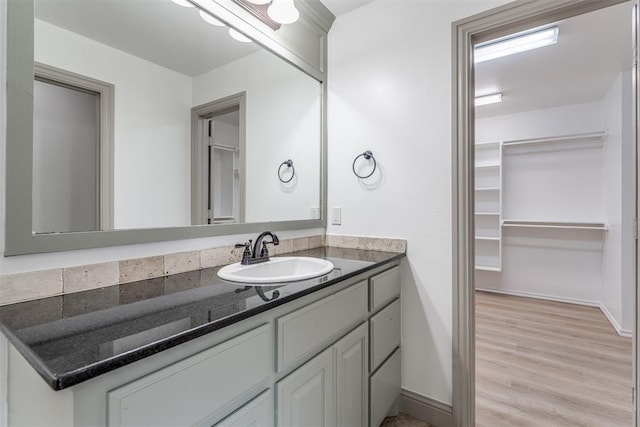 328 SW 175th Ter, Oklahoma City, OK 73170 - bathroom featuring vanity, wood finished floors, a walk in closet, and baseboards