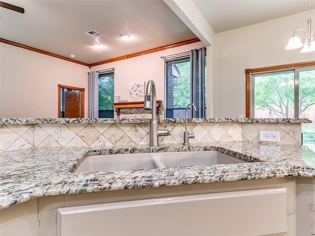 113 Stone Creek Dr, Midwest City, OK 73130 - kitchen with a sink, backsplash, a chandelier, light stone counters, and crown molding
