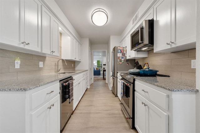7802 Old Hickory Ln, Oklahoma City, OK 73116 - kitchen featuring stainless steel appliances, a sink, decorative backsplash, and white cabinetry
