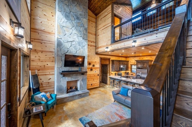 59 Sweet Elm, Broken Bow, OK 74728 - living room featuring a high ceiling, wood walls, concrete flooring, a stone fireplace, and wooden ceiling
