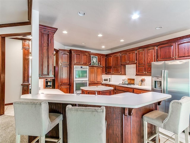 16441 Roserock Cir, Choctaw, OK 73020 - kitchen featuring appliances with stainless steel finishes, a peninsula, light countertops, recessed lighting, and a breakfast bar area