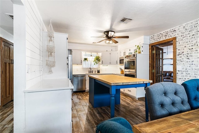 1113 Winnipeg Dr, Yukon, OK 73099 - kitchen with stainless steel appliances, wooden counters, a ceiling fan, a breakfast bar, and dark wood-style floors