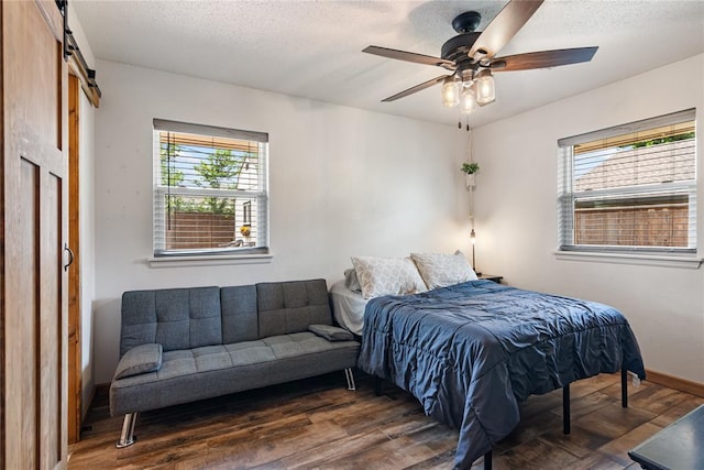 1113 Winnipeg Dr, Yukon, OK 73099 - bedroom with wood finished floors, a barn door, a textured ceiling, baseboards, and a ceiling fan