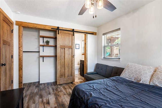 1113 Winnipeg Dr, Yukon, OK 73099 - bedroom with a barn door, dark wood-type flooring, ensuite bathroom, and ceiling fan