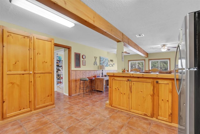 23596 Beach Haven Dr, Granite, OK 73547 - kitchen with freestanding refrigerator, a ceiling fan, a wainscoted wall, wooden walls, and a peninsula