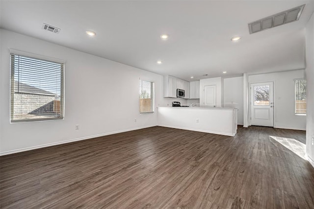 3717 Palmetto Bluff Dr, Mustang, OK 73064 - unfurnished living room featuring plenty of natural light, dark wood-style flooring, baseboards, and recessed lighting