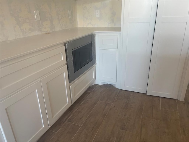 5100 Misty Wood Ln, Mustang, OK 73064 - kitchen view of wallpapered walls, stainless steel microwave, dark wood finished floors, light countertops, and white cabinetry