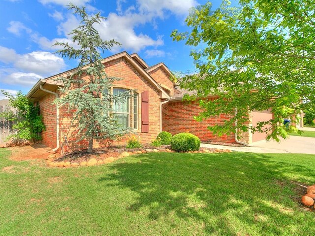 15508 Homecoming Dr, Edmond, OK 73013 - view of front of house with concrete driveway, brick siding, a front yard, and an attached garage
