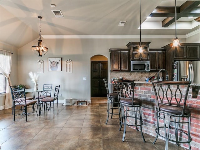 15508 Homecoming Dr, Edmond, OK 73013 - kitchen with appliances with stainless steel finishes, arched walkways, tasteful backsplash, a kitchen breakfast bar, and dark brown cabinets