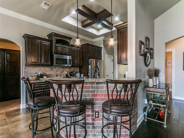 15508 Homecoming Dr, Edmond, OK 73013 - kitchen featuring appliances with stainless steel finishes, arched walkways, a breakfast bar, dark brown cabinets, and coffered ceiling