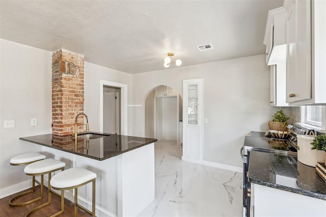 938 NE 21st St, Oklahoma City, OK 73105 - kitchen with a sink, baseboards, arched walkways, electric range, and dark stone counters
