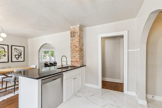 938 NE 21st St, Oklahoma City, OK 73105 - kitchen featuring dishwasher, arched walkways, a sink, white cabinets, and baseboards