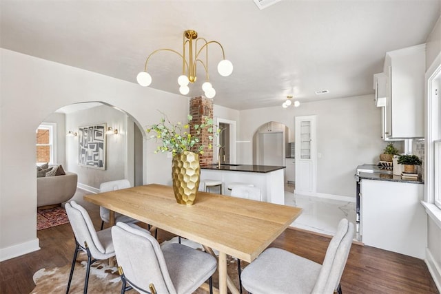 938 NE 21st St, Oklahoma City, OK 73105 - dining space featuring arched walkways, baseboards, and light wood-style floors
