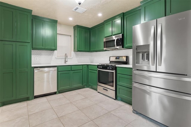1221 NW 101st St, Oklahoma City, OK 73114 - kitchen featuring stainless steel appliances, a sink, green cabinets, recessed lighting, and a textured ceiling