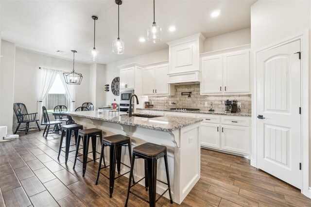 4442 Violet St, Tuttle, OK 73089 - kitchen featuring a sink, stainless steel microwave, tasteful backsplash, gas stovetop, and white cabinetry