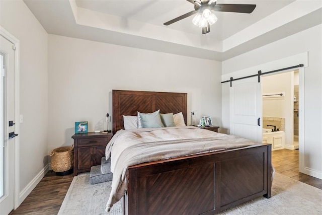 4442 Violet St, Tuttle, OK 73089 - bedroom with a barn door, a raised ceiling, wood finished floors, and baseboards