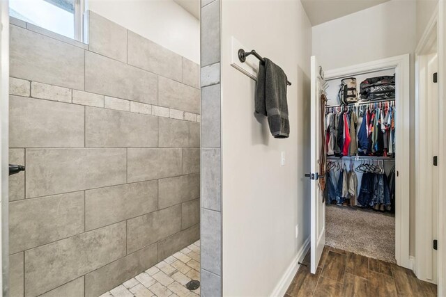 4442 Violet St, Tuttle, OK 73089 - bathroom with wood finished floors, a tile shower, a spacious closet, and baseboards
