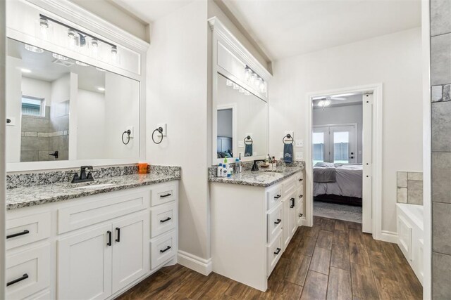 4442 Violet St, Tuttle, OK 73089 - bathroom featuring wood finished floors, two vanities, tiled shower, a ceiling fan, and connected bathroom
