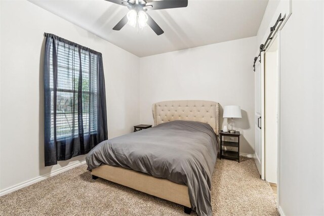 4442 Violet St, Tuttle, OK 73089 - bedroom featuring a barn door, light carpet, baseboards, and a ceiling fan