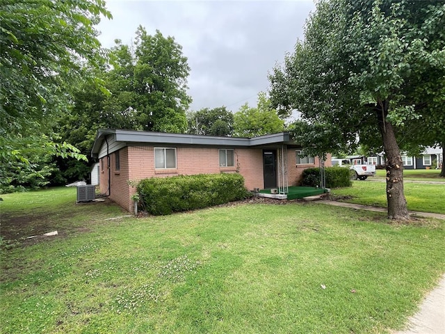 403 NW 3rd St, Minco, OK 73059 - view of front of property featuring brick siding, cooling unit, and a front lawn
