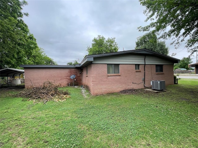 403 NW 3rd St, Minco, OK 73059 - view of side of home with cooling unit, brick siding, a yard, and a detached carport