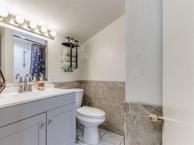 2133 SW 46th St, Oklahoma City, OK 73119 - full bath with tile walls, toilet, vanity, a wainscoted wall, and tile patterned flooring