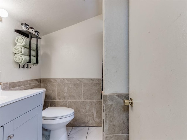 2133 SW 46th St, Oklahoma City, OK 73119 - bathroom with tile walls, vanity, toilet, and wainscoting