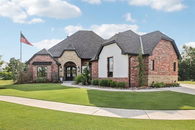 5813 Tiger Stone Dr, Mustang, OK 73064 - view of front of house featuring a front lawn, stone siding, a shingled roof, and brick siding