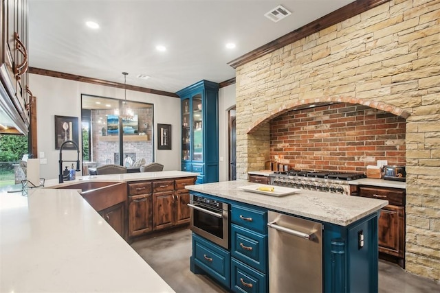 5813 Tiger Stone Dr, Mustang, OK 73064 - kitchen with blue cabinets, concrete flooring, a sink, crown molding, and hanging light fixtures