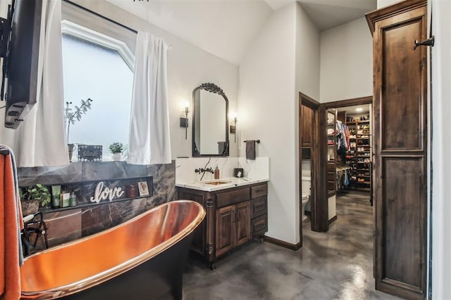 5813 Tiger Stone Dr, Mustang, OK 73064 - full bath with a freestanding tub, concrete floors, vanity, vaulted ceiling, and a spacious closet