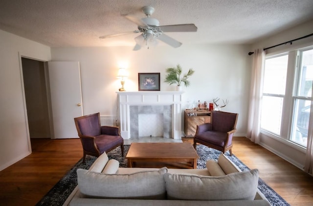 2616 NW 33rd St, Oklahoma City, OK 73112 - living room featuring a textured ceiling, wood finished floors, baseboards, a premium fireplace, and a ceiling fan