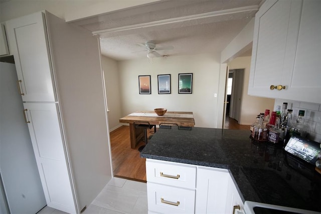 2616 NW 33rd St, Oklahoma City, OK 73112 - kitchen with a peninsula, ceiling fan, white cabinets, dark stone countertops, and light tile patterned floors