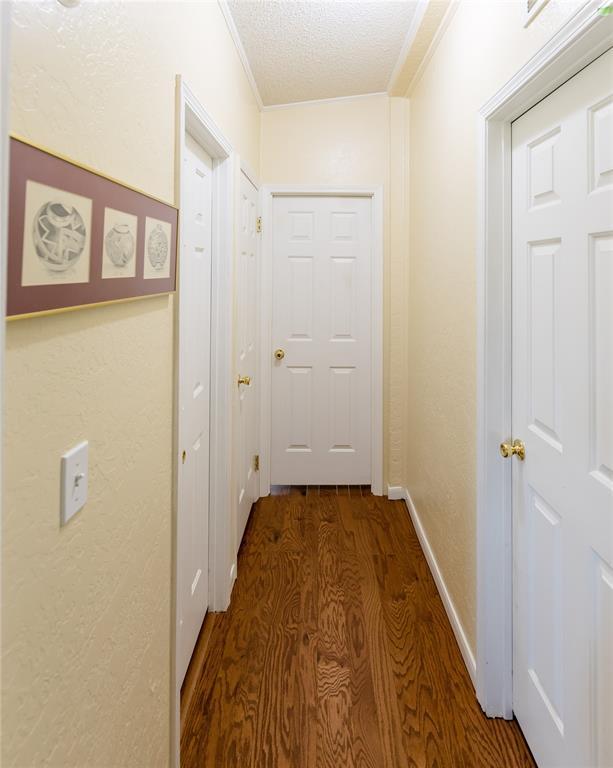 711 Sisson Ave, Sayre, OK 73662 - hall with wood finished floors, ornamental molding, a textured ceiling, and baseboards