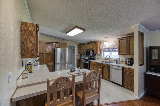 711 Sisson Ave, Sayre, OK 73662 - kitchen featuring appliances with stainless steel finishes, a sink, a textured ceiling, light countertops, and a peninsula