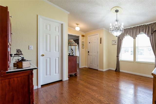 711 Sisson Ave, Sayre, OK 73662 - dining space featuring a chandelier, a textured ceiling, ornamental molding, dark wood-type flooring, and baseboards