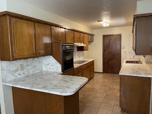 7716 S Charlotte Dr, Oklahoma City, OK 73159 - kitchen with black appliances, a textured ceiling, a sink, backsplash, and light countertops