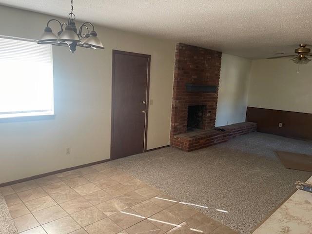 7716 S Charlotte Dr, Oklahoma City, OK 73159 - unfurnished living room with a textured ceiling, a chandelier, a brick fireplace, and ceiling fan