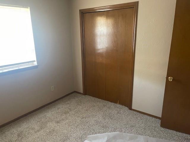 7716 S Charlotte Dr, Oklahoma City, OK 73159 - unfurnished bedroom featuring light colored carpet, a closet, and baseboards