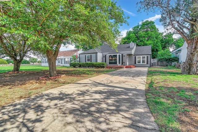 1016 E Cypress St, Altus, OK 73521 - view of front facade with driveway, roof with shingles, a front yard, and a chimney