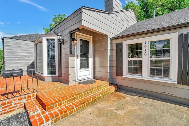 1016 E Cypress St, Altus, OK 73521 - property entrance featuring roof with shingles, a chimney, and a patio