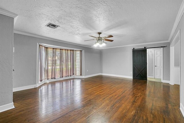 1016 E Cypress St, Altus, OK 73521 - spare room featuring a ceiling fan, a barn door, wood-type flooring, baseboards, and a textured ceiling
