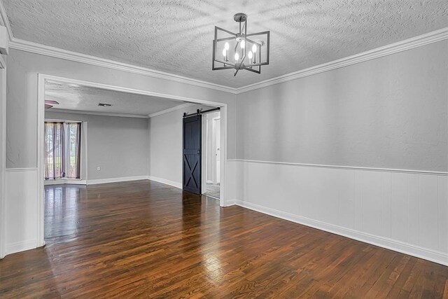 1016 E Cypress St, Altus, OK 73521 - spare room featuring a textured ceiling, a barn door, wood finished floors, a chandelier, and crown molding