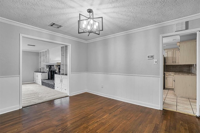 1016 E Cypress St, Altus, OK 73521 - unfurnished dining area featuring hardwood / wood-style flooring, a textured ceiling, a brick fireplace, a chandelier, and a wainscoted wall