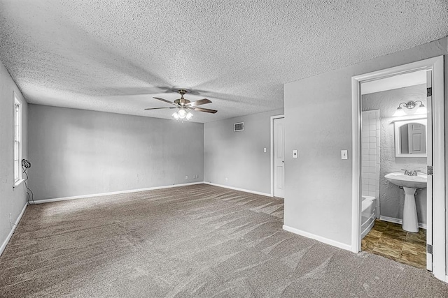 1016 E Cypress St, Altus, OK 73521 - spare room featuring a ceiling fan, carpet, a textured ceiling, a sink, and baseboards