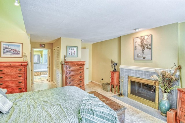 3605 Hampton Ct, Norman, OK 73072 - bedroom with a textured ceiling, a tile fireplace, connected bathroom, tile patterned floors, and a closet