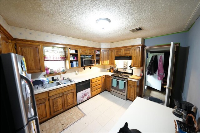 kitchen with stainless steel appliances, brown cabinets, light countertops, and a textured ceiling